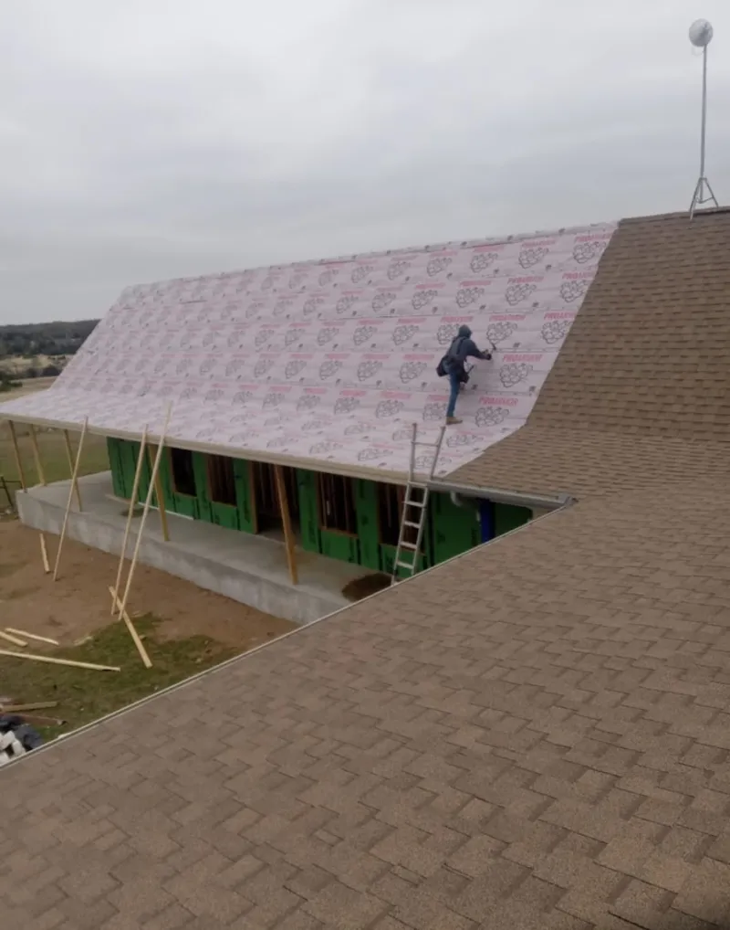 Worker preparing underlayment for a metal roof installation in Kingsland